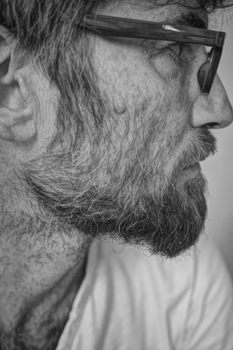 A bearded man in glasses, in profile, black and white.