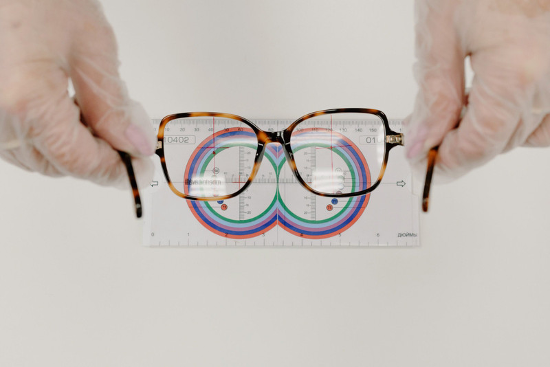 An optician measuring tortoise frames with a lens ruler.
