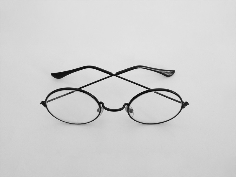 Oval black wire frames, temples crossed.