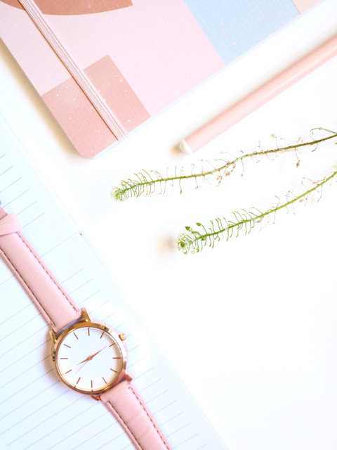 The rose gold watch on a pastel desk.