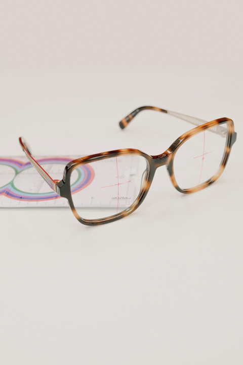 Tortoiseshell square frames beside a lens ruler.