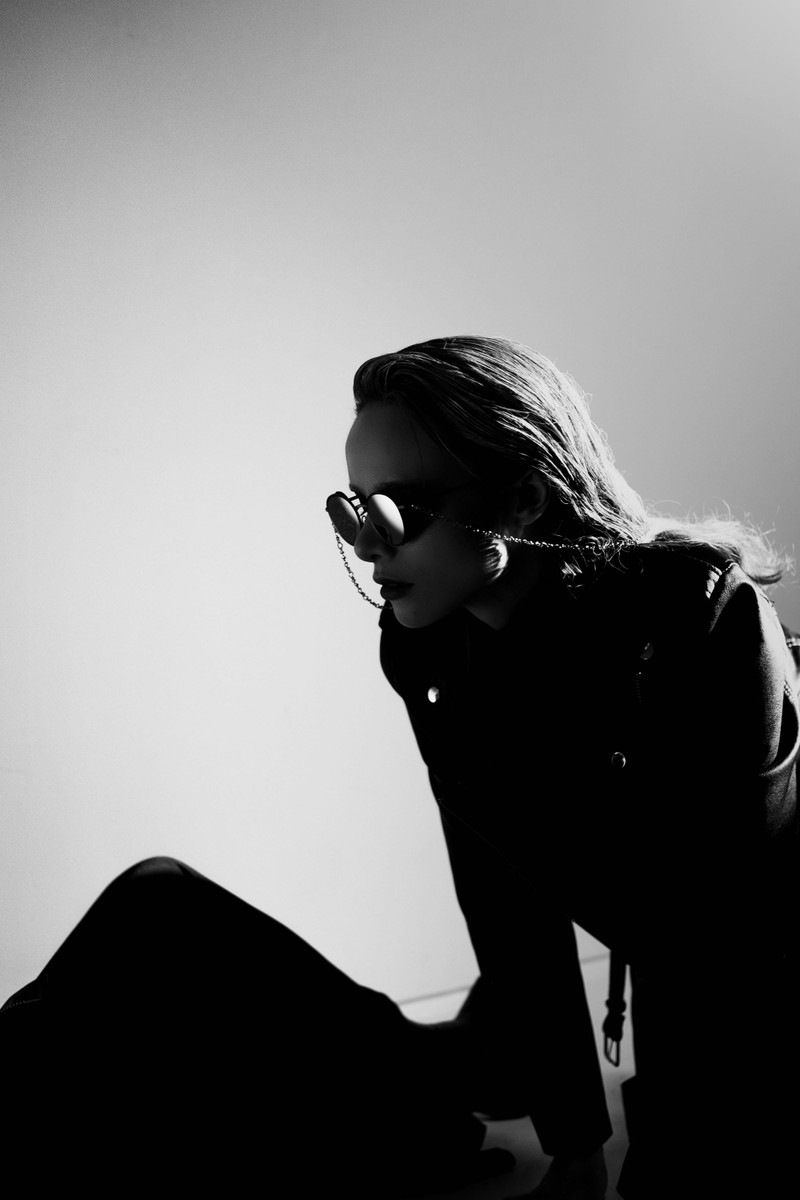 A woman in sunglasses in hard light, black and white.