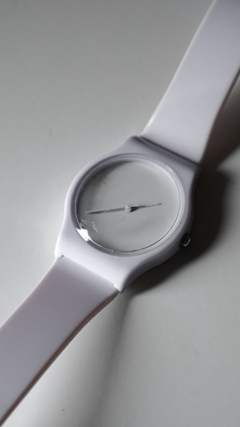 A white watch with no numerals, close.