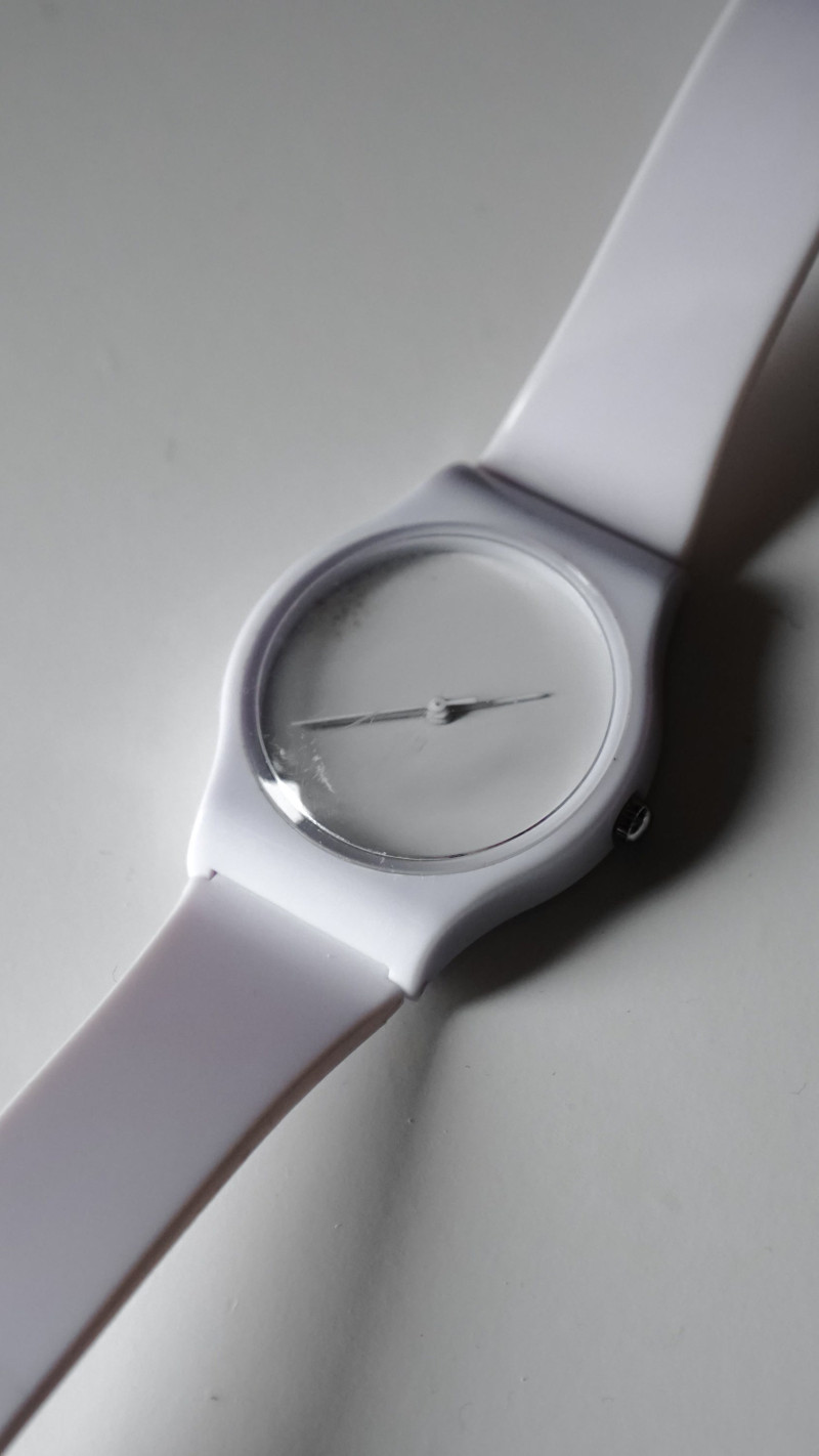 A white watch with no numerals, close.
