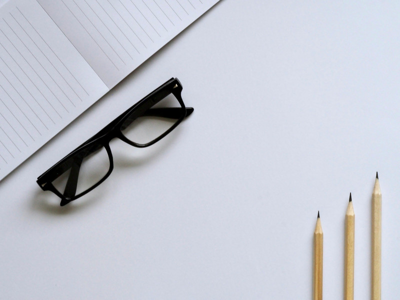 Black acetate frames on a notebook with pencils.