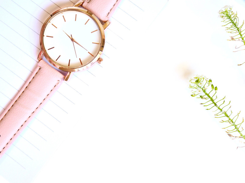 A rose gold watch on a pink strap with flowers.